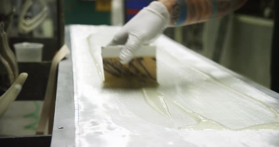 A man using a brush to apply glue to a panel