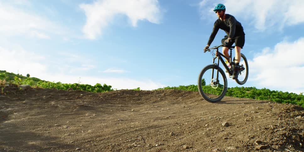 A man with a helmet and sunglasses riding a bike on dirt