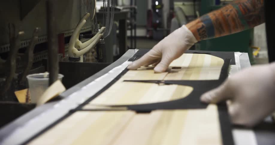 A man is working placing a board on a machine