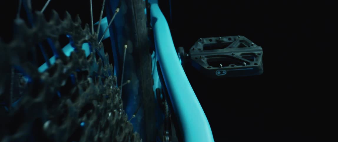 A bicycle is illuminated by a blue light in a pitch black room