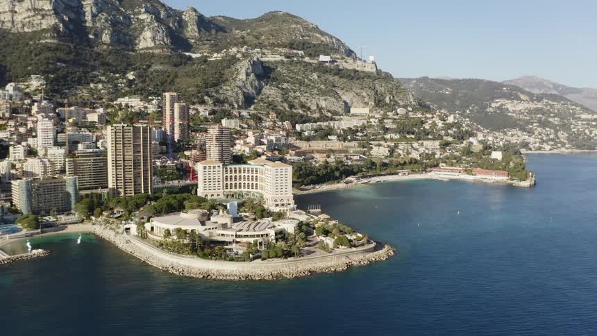 A coastal city with buildings and trees with a mountain range and the sky in the background