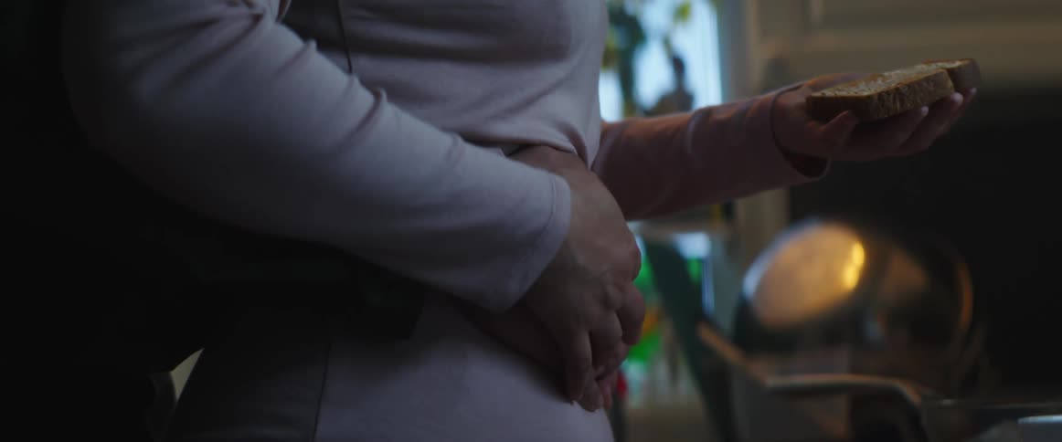 A couple holding each other as the female prepares bread