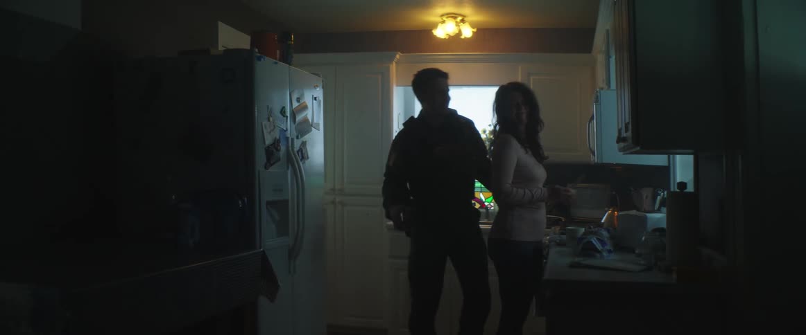 Police officer back hugs wife cooking in kitchen before leaving
