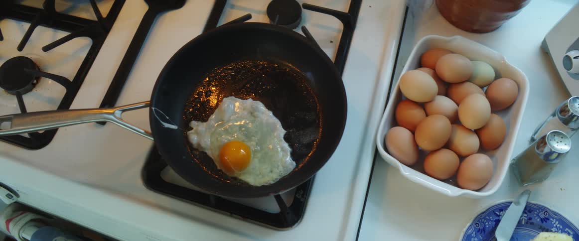 A woman puts salt on a cooking egg