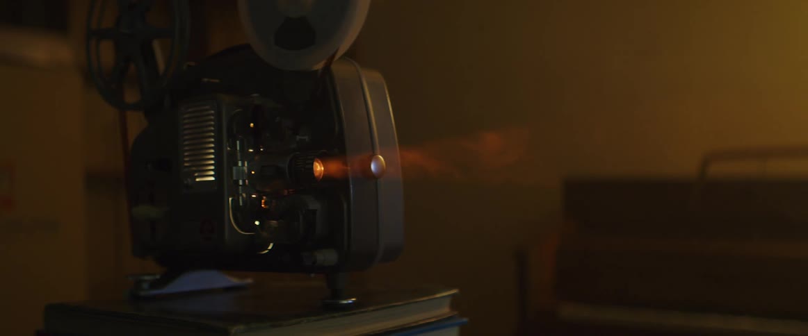 A movie projector playing on a stack of books in a room