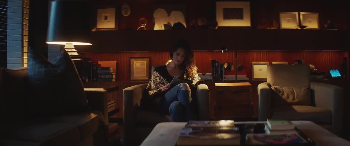 A woman views media on a tablet while sitting in a study