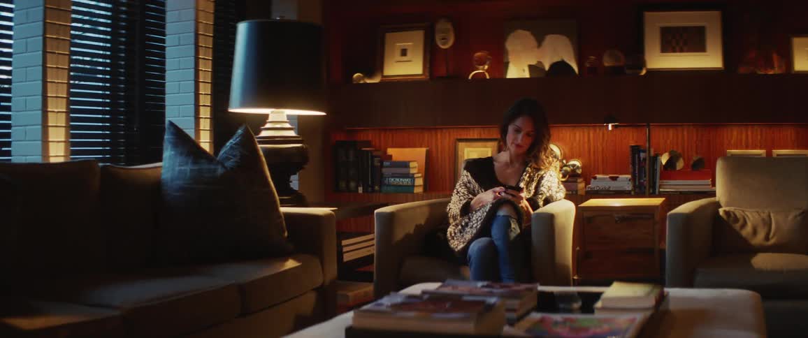 A woman is sitting in the living room using her phone