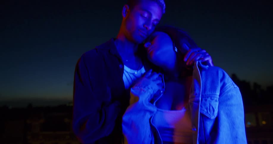 A man and woman are standing outdoors at night