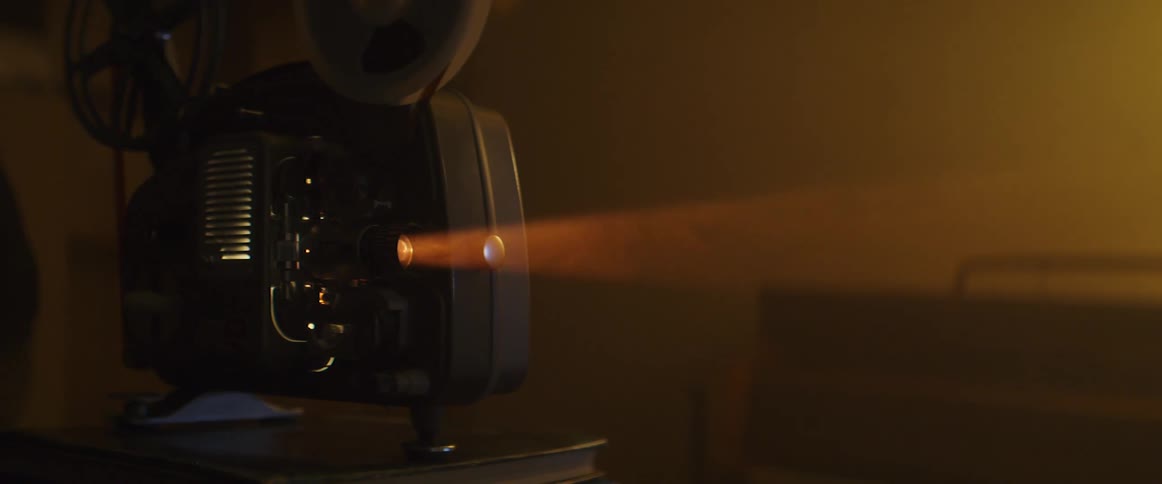 A film projector on a book projecting with a person and a door in the background