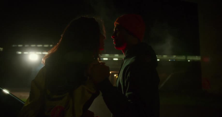 Young couple looking into each others eyes at night in front of passing train