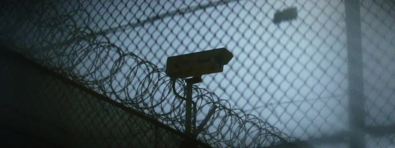 A video camera mounted on a fence with razor wire