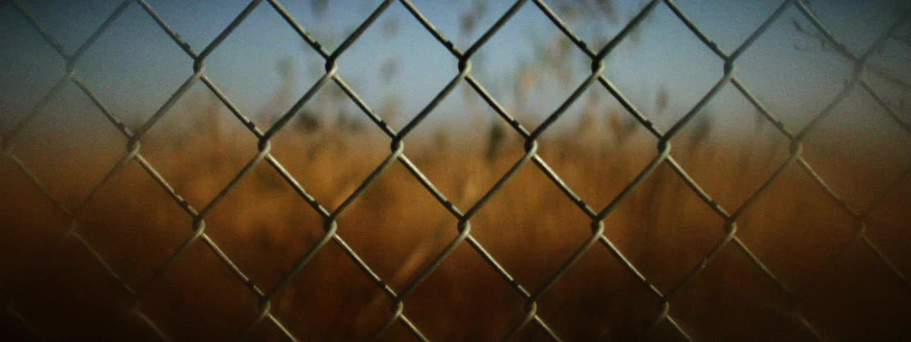 A fence in front of a grassy field