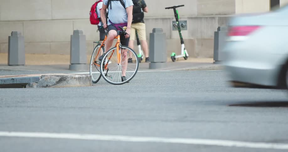 Multiple people stand at a busy intersection waiting to cross