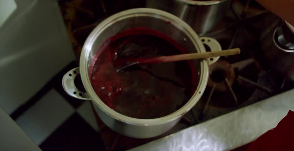 A cook is stirring a pot with a spoon