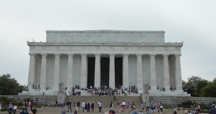 People walking around and sitting at a monument