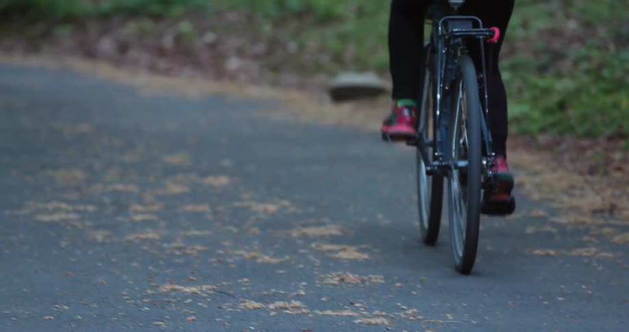 Woman with pink shoes and tights cycles on a country road