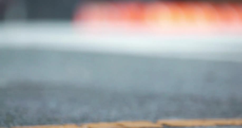 Close up of a bike on the pavement going by with a person walking in the background and a car driving