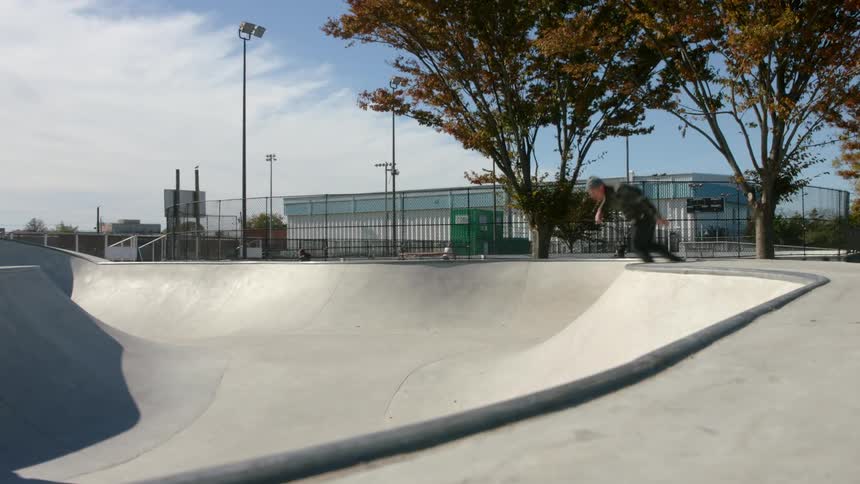 A man is skateboarding in a park on a cloudy day
