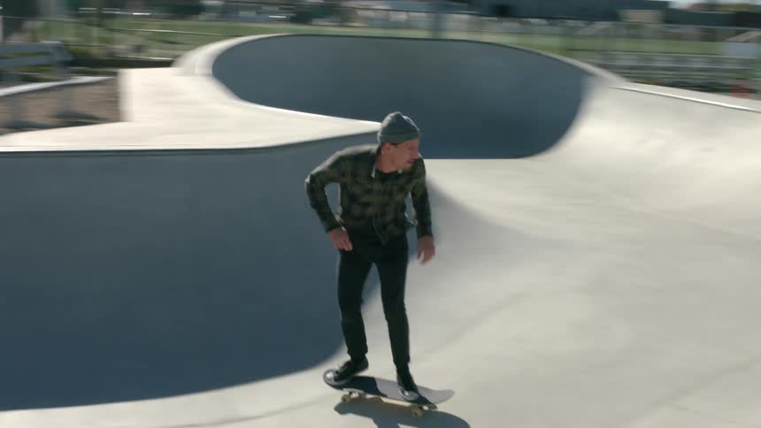 A man in a plaid shirt performs skateboard tricks
