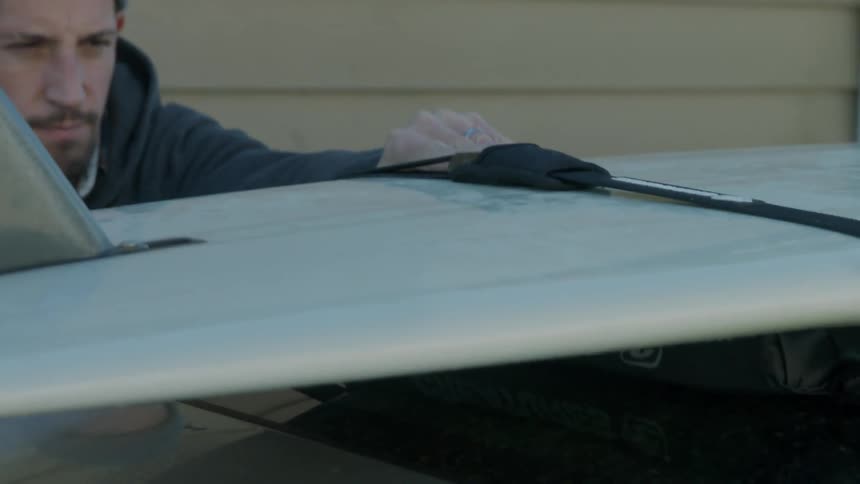 A man tightens the harness on a surfboard