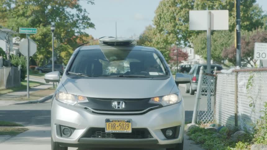 A car backs out of a driveway and travels down a street