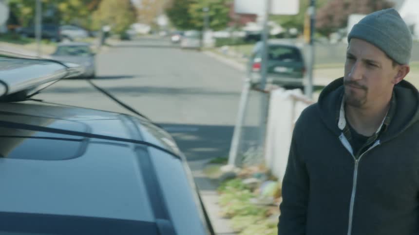 A man checks the surfboard on top of a vehicle