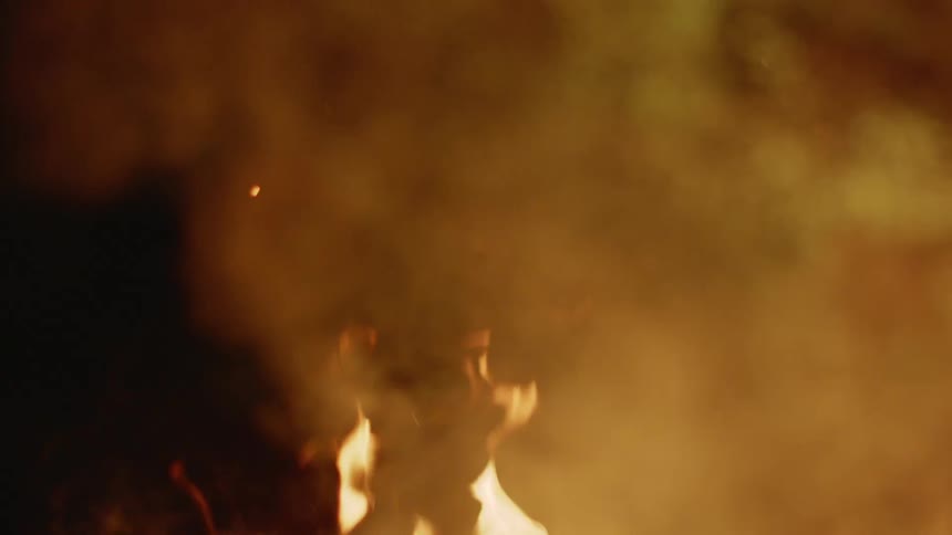 Smoke floats above a burning fire at night