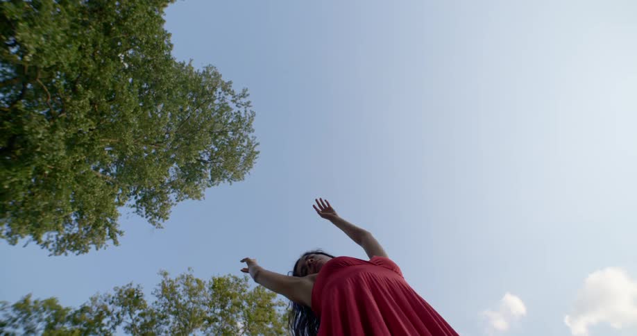 A young woman dancing outside under trees