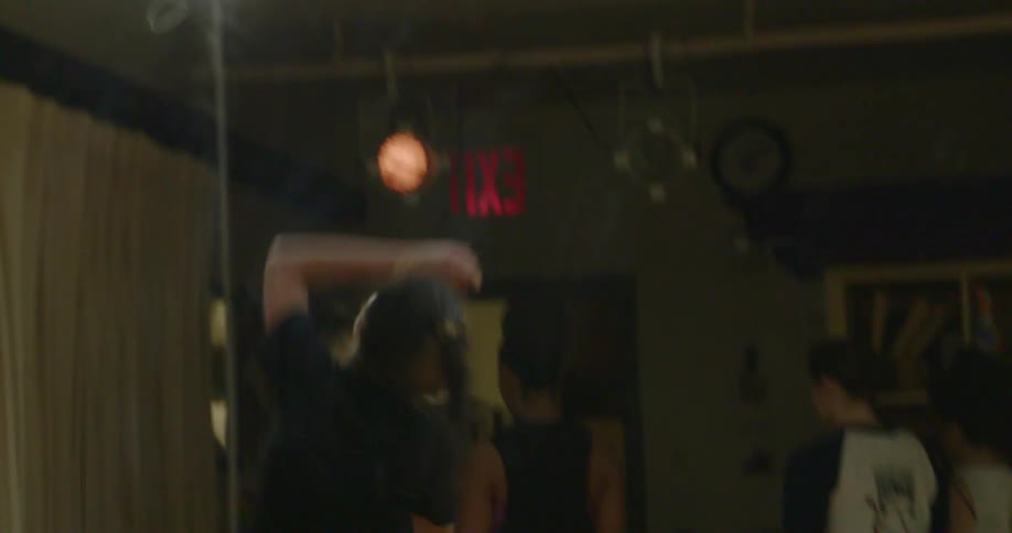 A young woman dances and spins in dance class as other students stand in a line facing the other direction