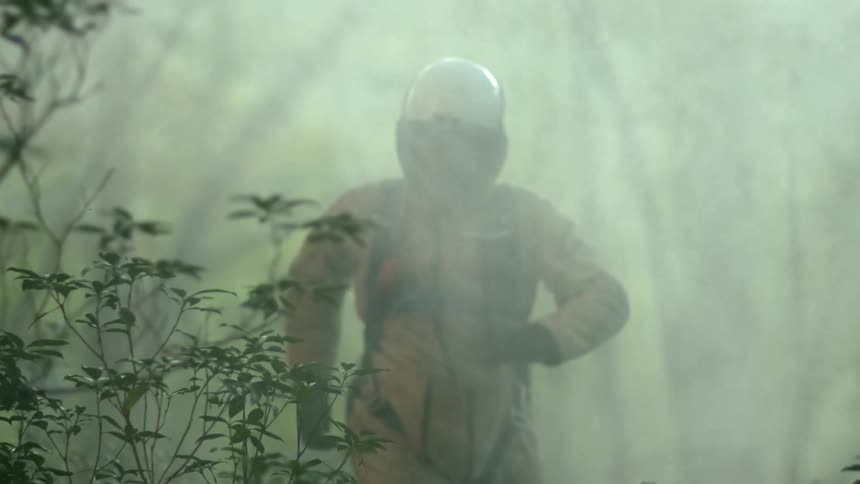 Man in a vintage flight suit runs throught the mist in a forest