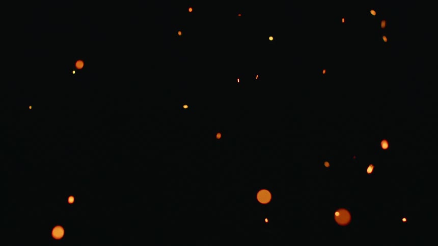 Orange circles and sparks flying around in the air in darkness
