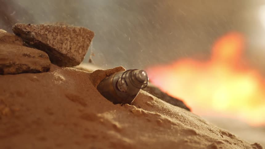 Fire burns while particles fall onto mound obscuring conical nose object