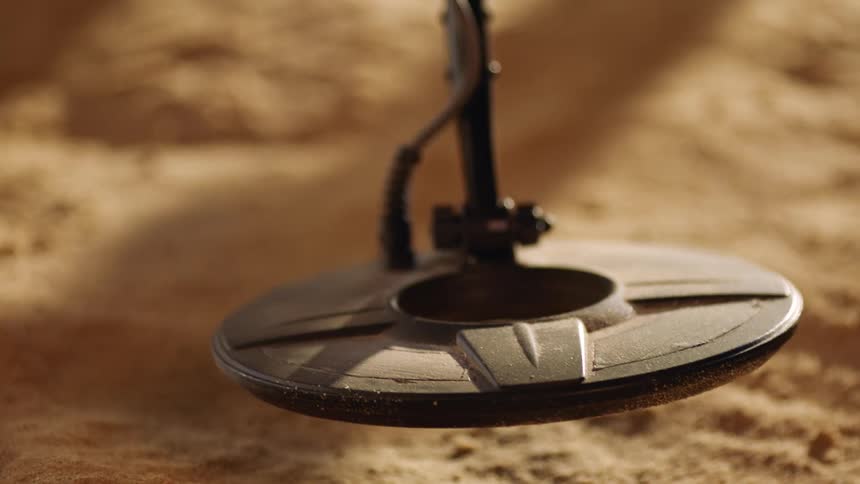A metal detector being used over sand