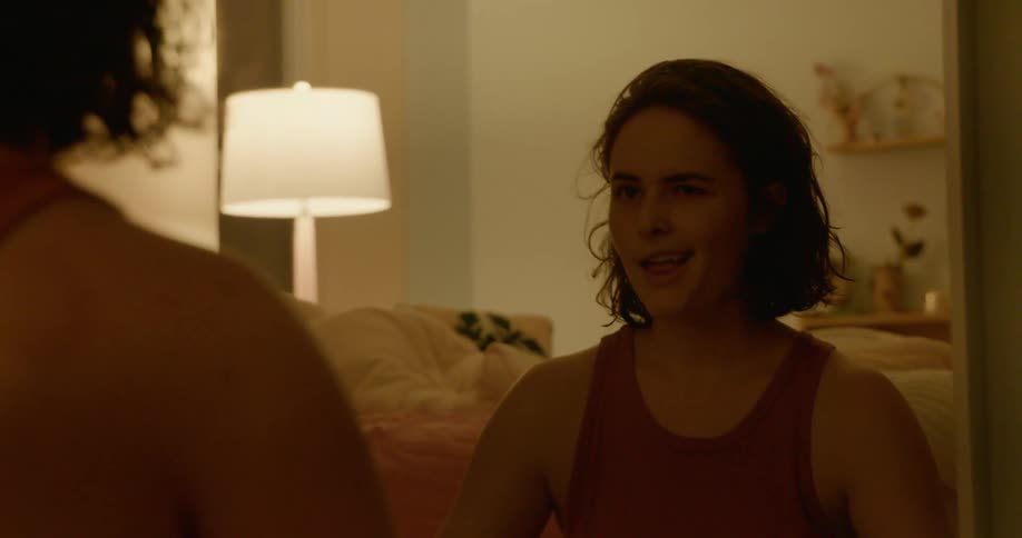 A female caucasian sitting on the floor flexing her arms in a mirror