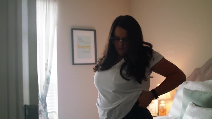 A woman stands in her bedroom and puts her prosthetic legs on