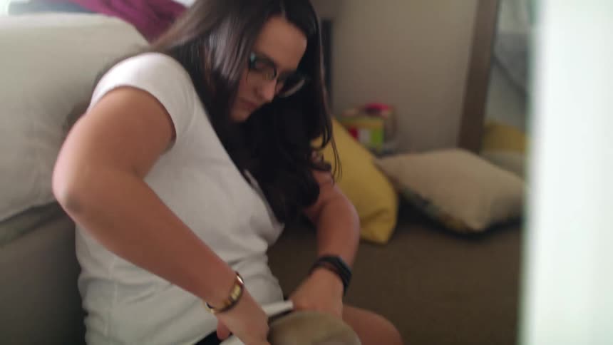 A young woman at home prepares to put on her prosthetic leg