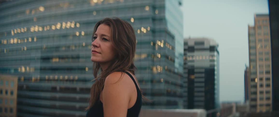 A woman stands on a downtown rooftop and looks around