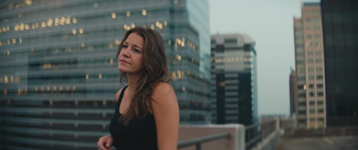 A woman is standing outdoors in a downtown city