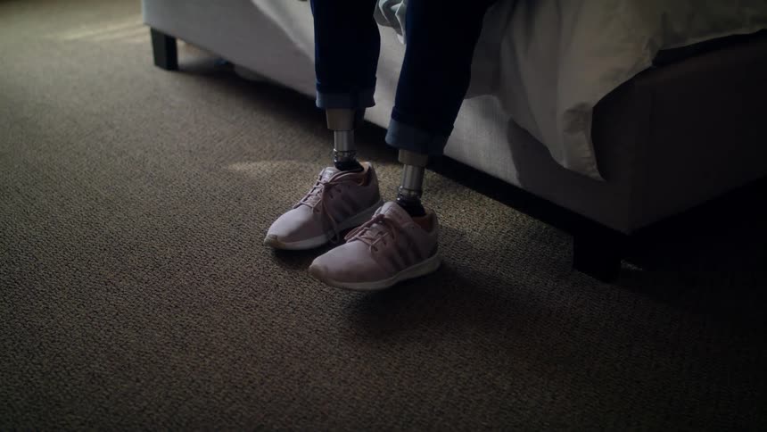 A person with prosthetic legs sitting on a sofa indoors
