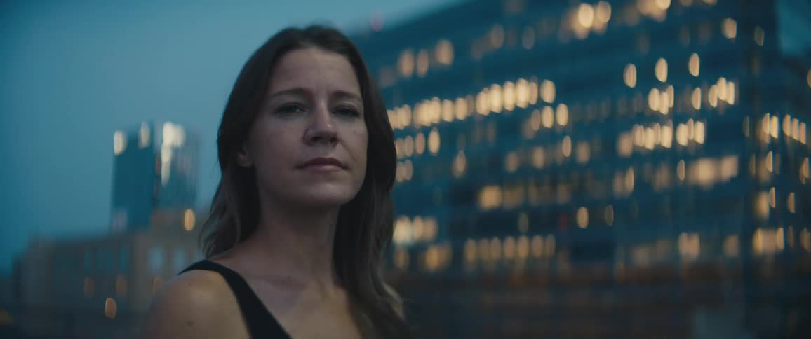 A woman standing in front of a lit up building in a city