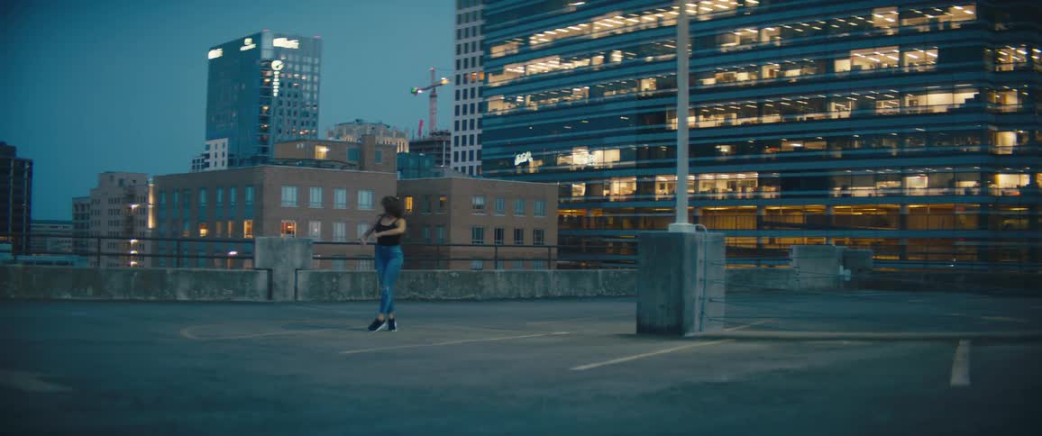 A woman is dancing in a downtown city at dusk