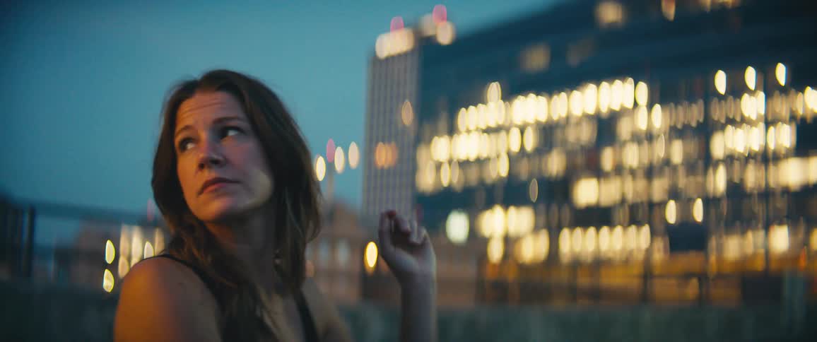 A brunette caucasian female sitting and then standing up outside