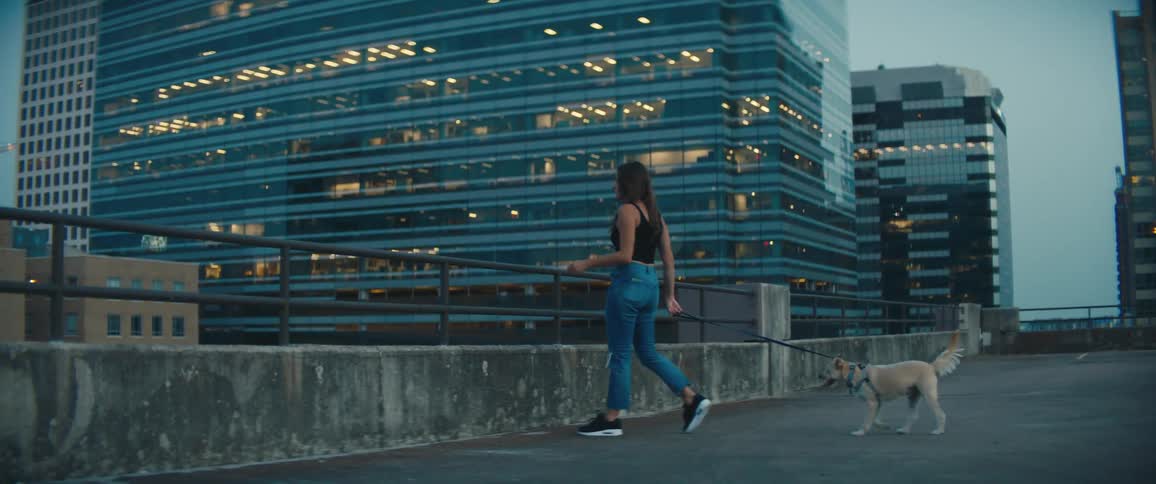 A woman is walking her dog in a downtown city