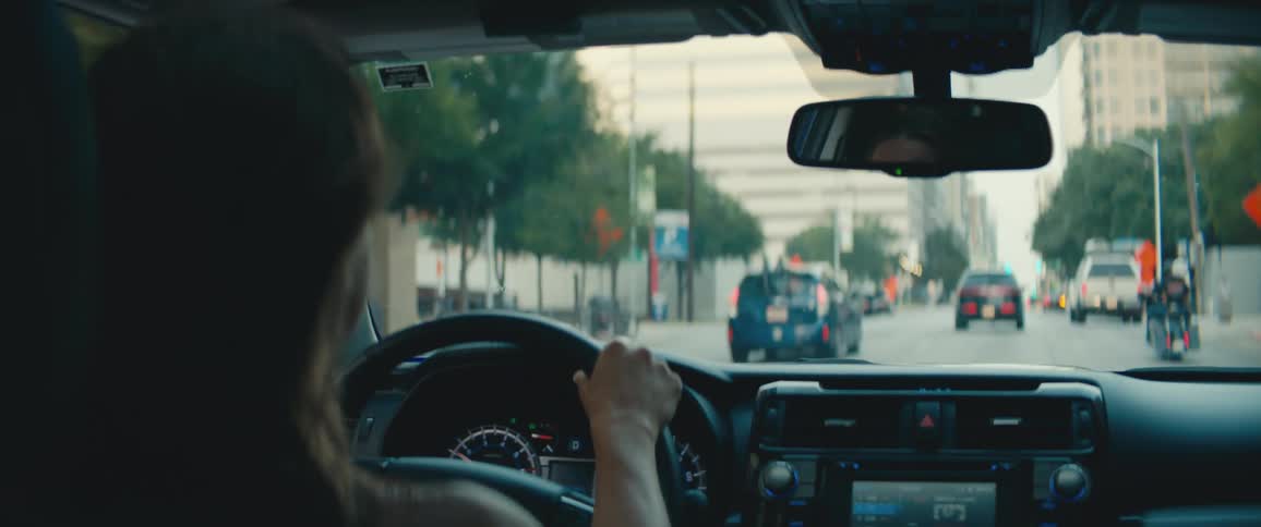 Female driver turns the steering wheel in order to make the car go on a city highway