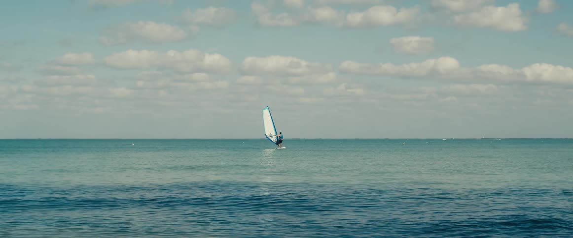 A man is wind surfing out upon the ocean on a windy day
