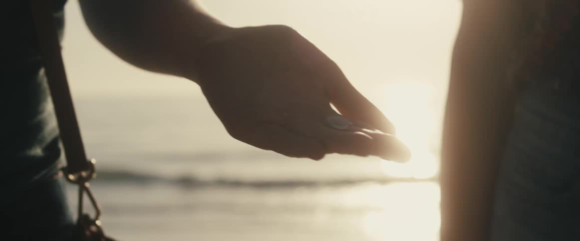 Two people on a beach and one is holding something in a hand