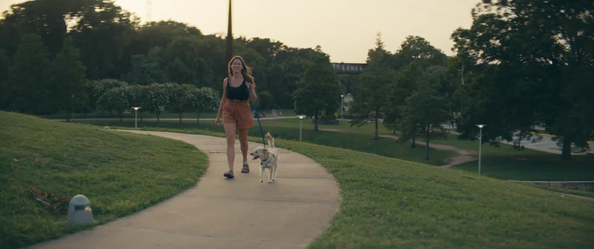 A female caucasian walking her dog in a park