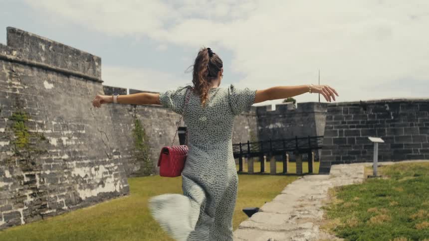 A young woman walks through a historical site on a very windy day