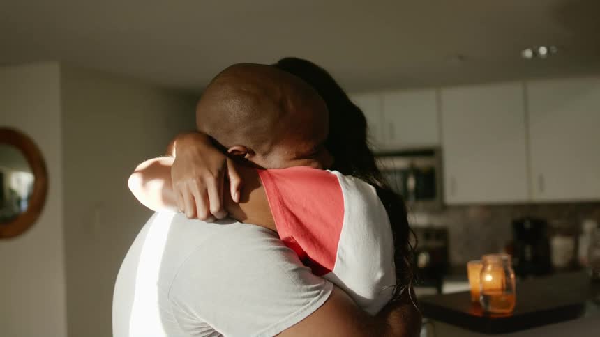 A couple standing in a kitchen holding and hugging each other