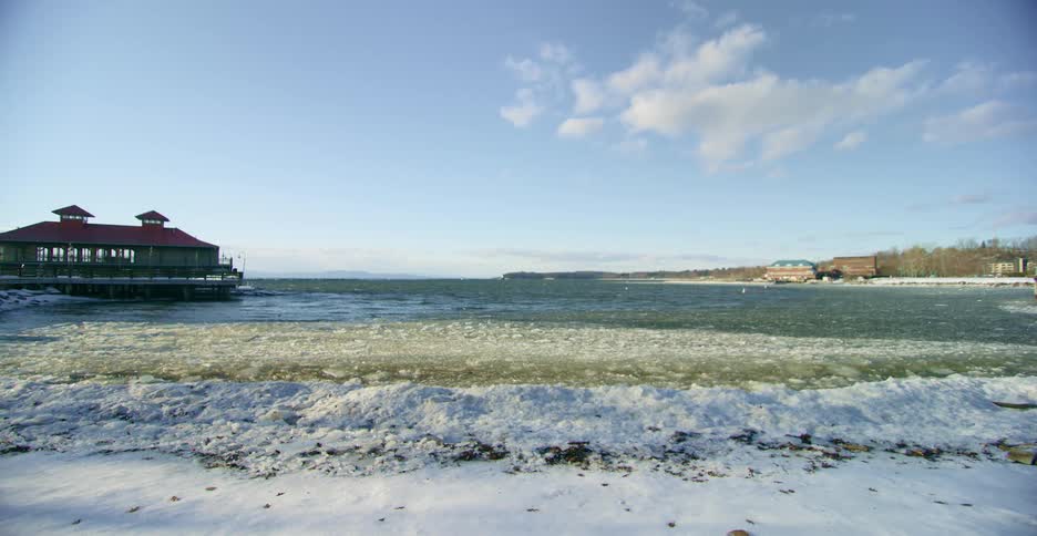Waves rolling in to the shore with a building in the background